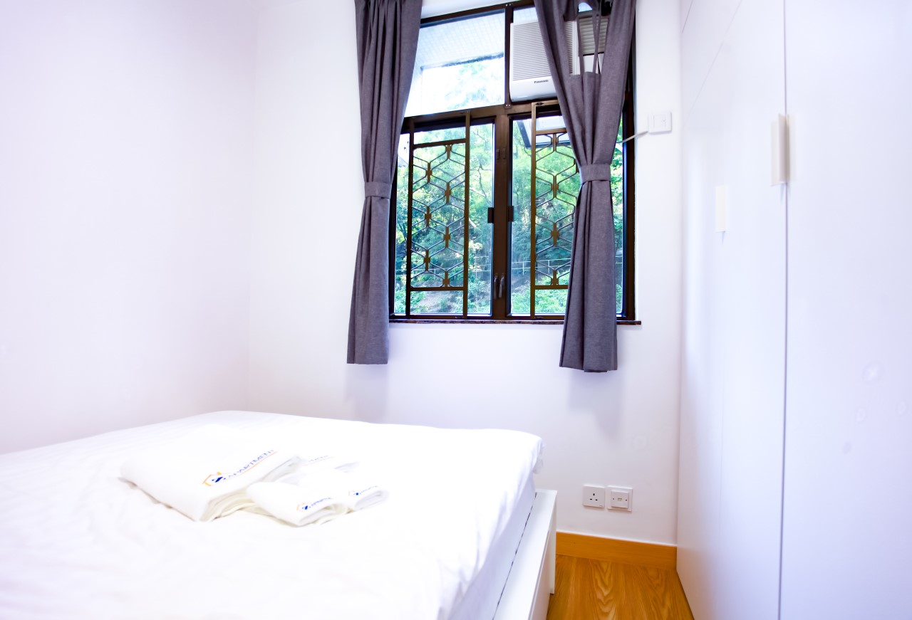 Queen size bed facing window in Tai Hang Serviced Apartment Hong Kong