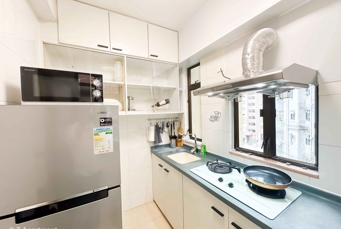 Modern kitchen with gas stove, range hood, microwave oven, fridge in 2 bedrooms apartment Tin Hau