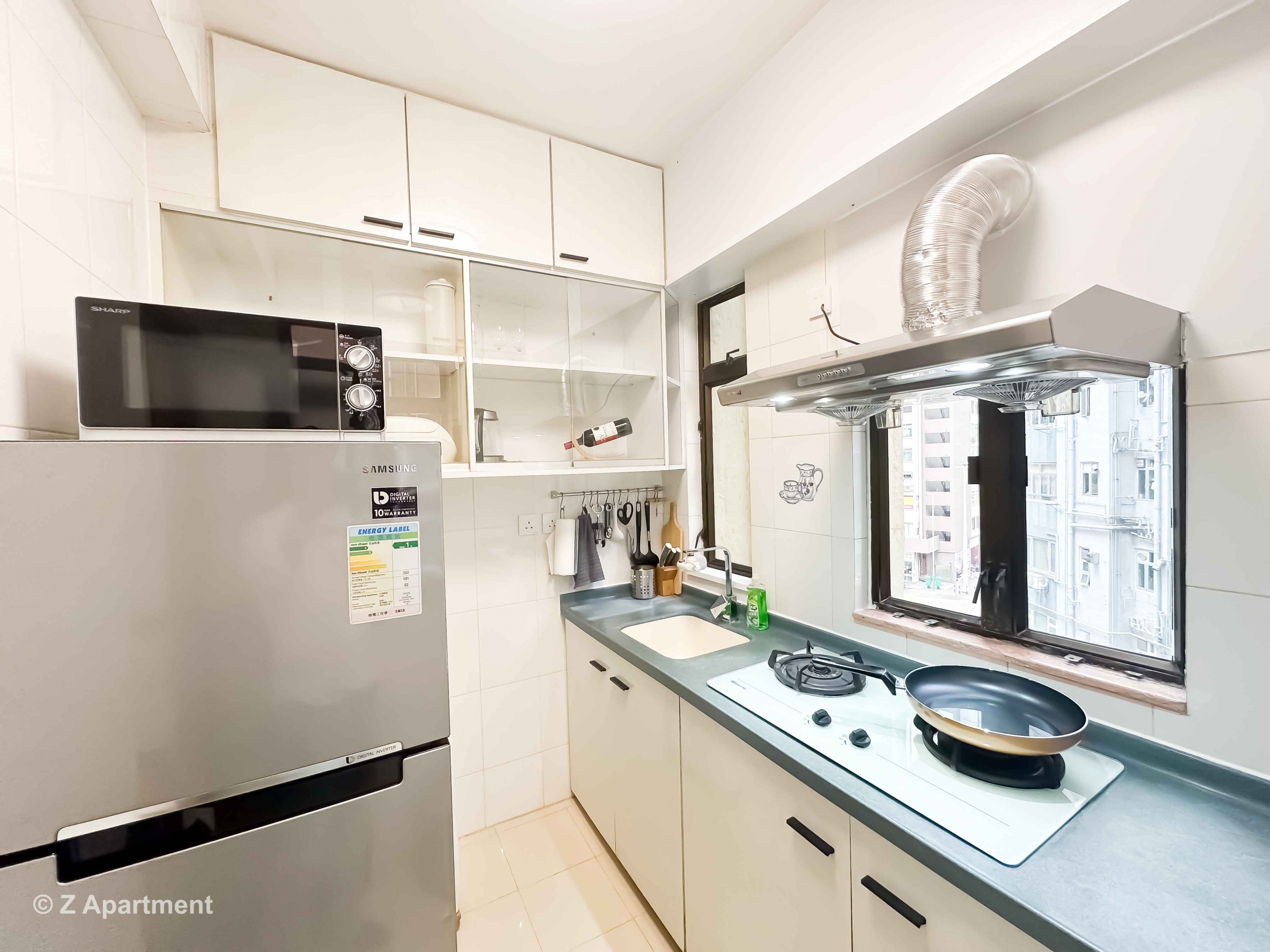 Modern kitchen with gas stove, range hood, microwave oven, fridge in 2 bedrooms apartment Tin Hau