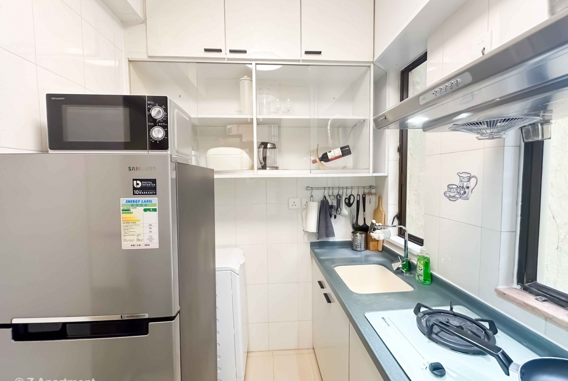 Modern kitchen with gas stove, range hood, microwave oven, fridge, washing machine in 2 bedrooms apartment Tin Hau