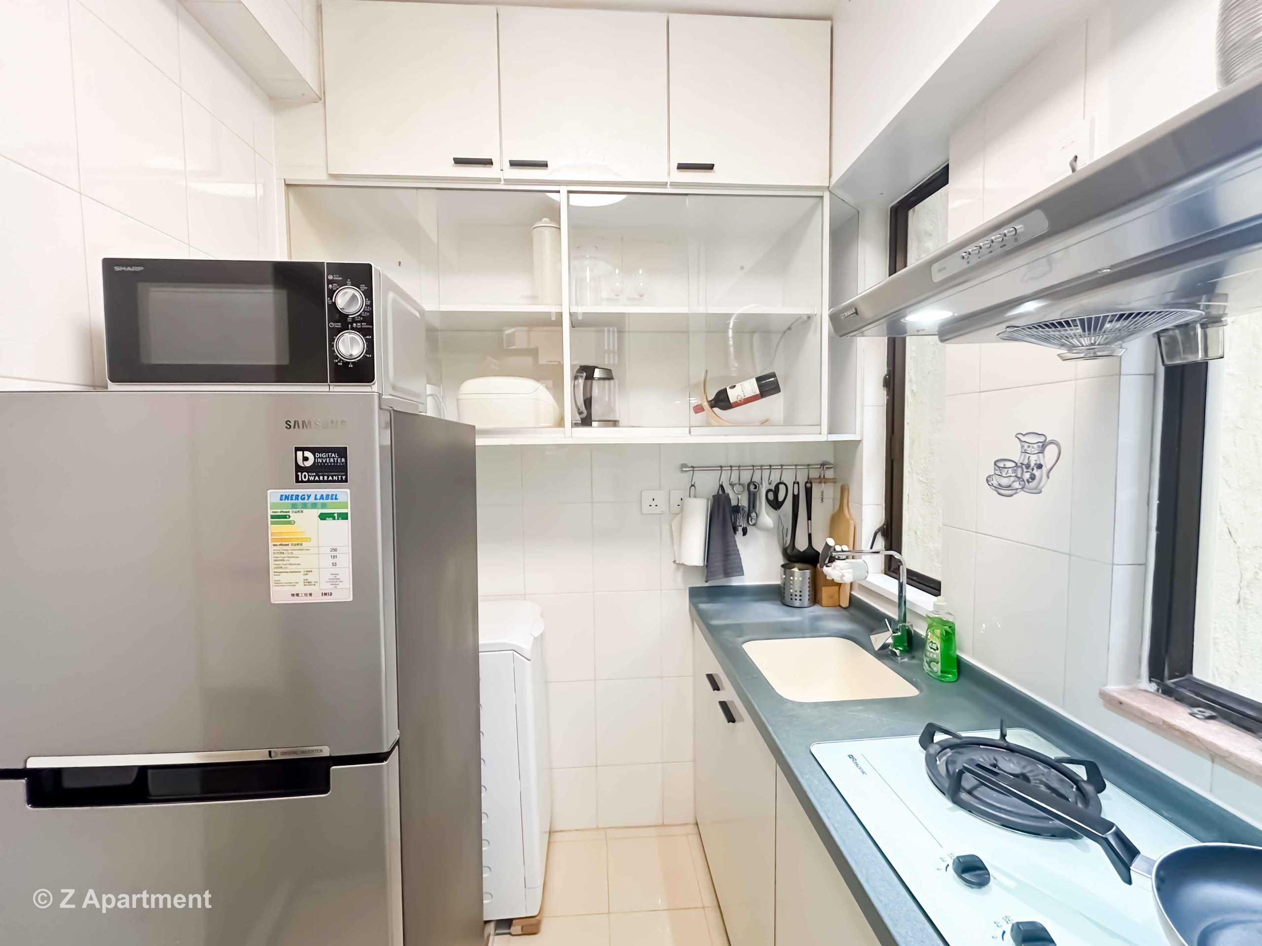 Modern kitchen with gas stove, range hood, microwave oven, fridge, washing machine in 2 bedrooms apartment Tin Hau